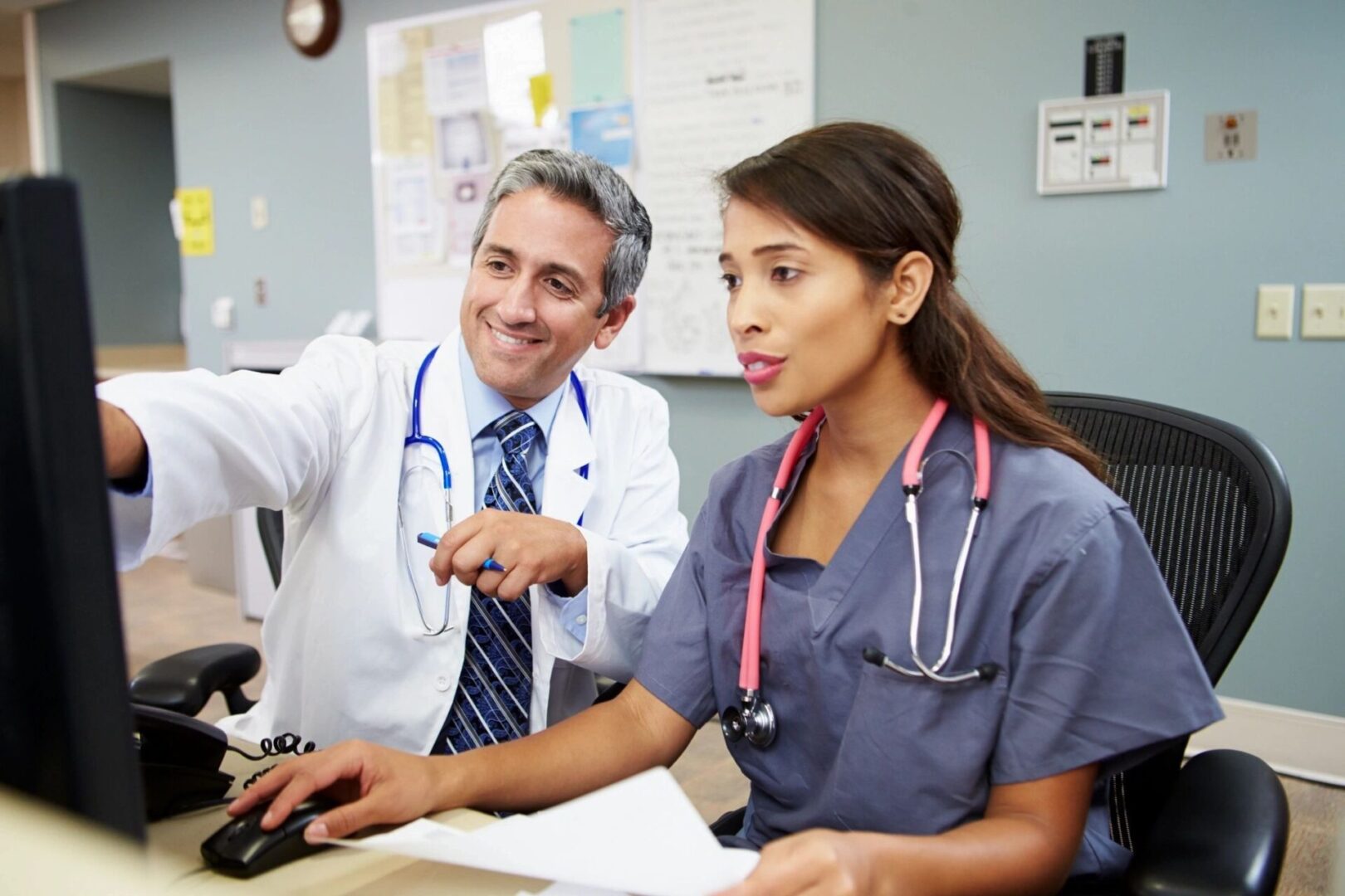 A doctor and nurse are sitting at the desk.